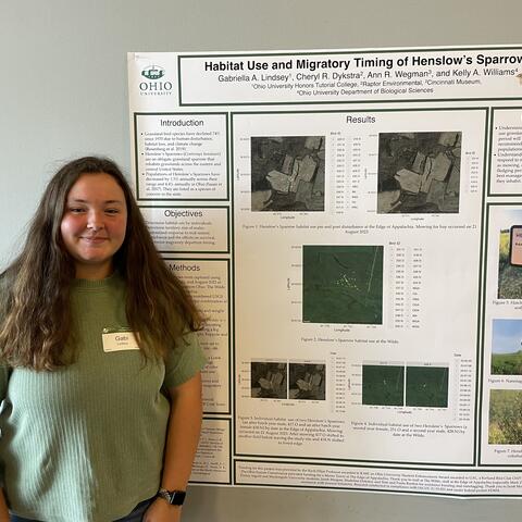 Gabi Lindsey poses smiling in front of her poster.